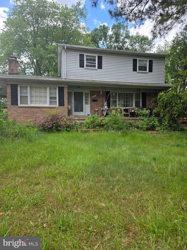 9517 Nordic Dr, Lanham, MD 20706 - traditional-style home with covered porch, brick siding, and a chimney