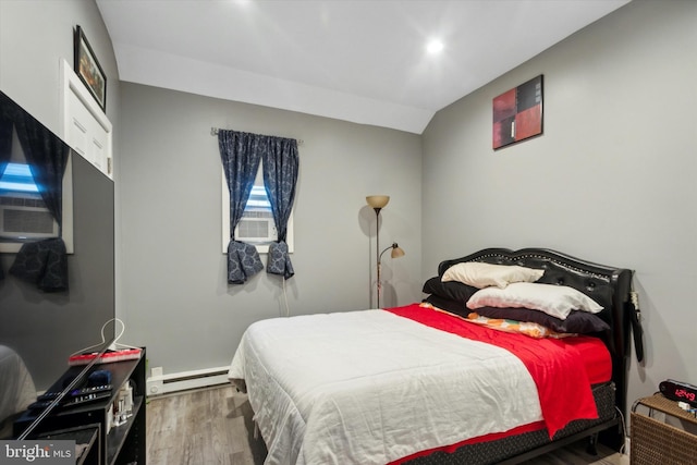 bedroom with hardwood / wood-style flooring, lofted ceiling, and a baseboard heating unit