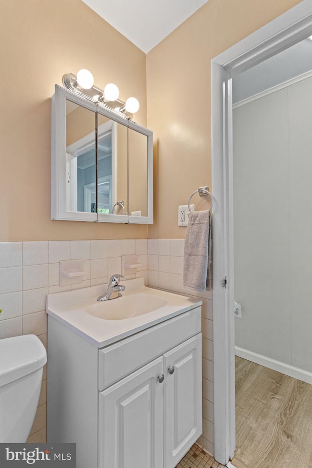 bathroom featuring vanity, hardwood / wood-style flooring, toilet, and tile walls