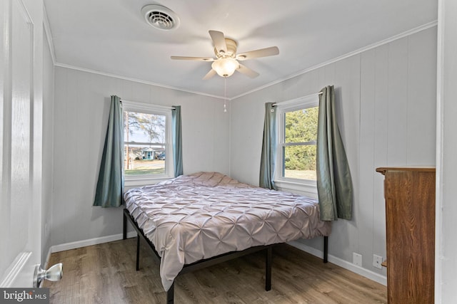 bedroom featuring multiple windows, hardwood / wood-style flooring, ceiling fan, and crown molding