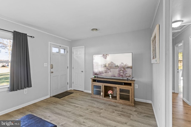 foyer featuring plenty of natural light, light wood-type flooring, and crown molding