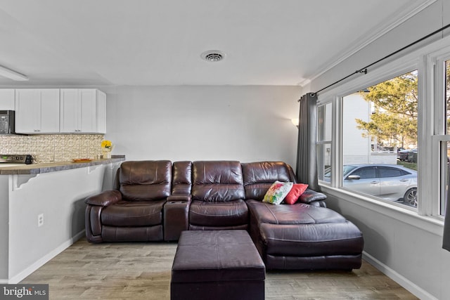 living room with crown molding and light hardwood / wood-style floors