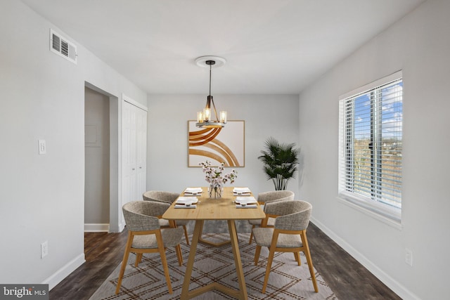 dining space with dark hardwood / wood-style flooring and a chandelier