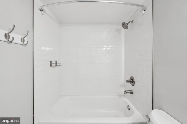 bathroom featuring toilet and tiled shower / bath