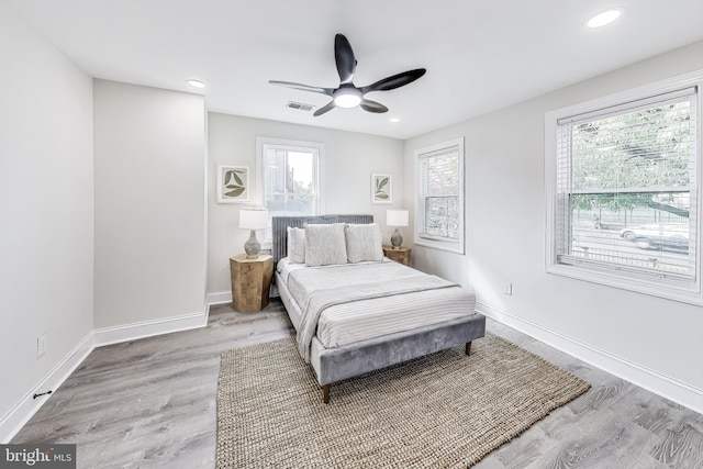 bedroom with ceiling fan, light hardwood / wood-style floors, and multiple windows