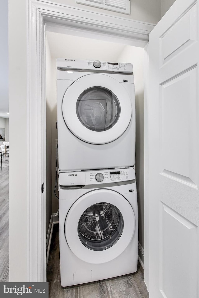 washroom featuring dark hardwood / wood-style flooring and stacked washer / drying machine