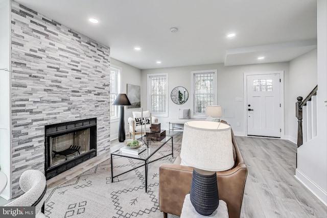 living room featuring a healthy amount of sunlight, light wood-type flooring, and a tiled fireplace