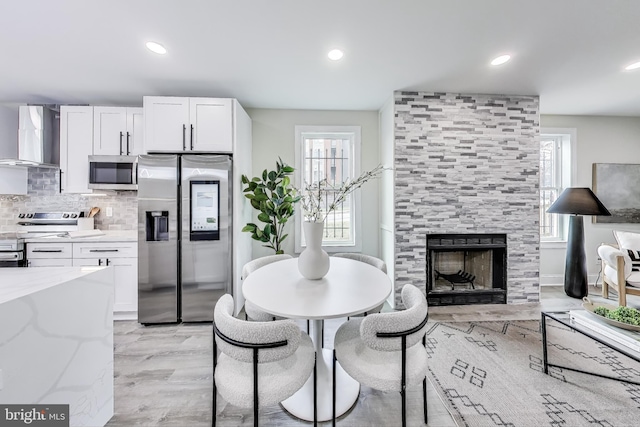 dining room featuring light wood-type flooring, a fireplace, and a wealth of natural light