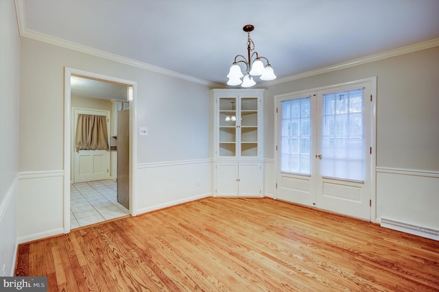 unfurnished dining area featuring light hardwood / wood-style floors, ornamental molding, and an inviting chandelier