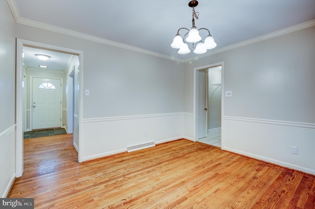 spare room with ornamental molding, light hardwood / wood-style floors, and a notable chandelier