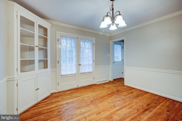 unfurnished dining area featuring ornamental molding, light wood-type flooring, a baseboard radiator, and a notable chandelier