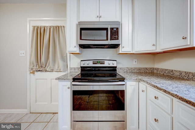 kitchen featuring stainless steel appliances, white cabinetry, and light stone counters