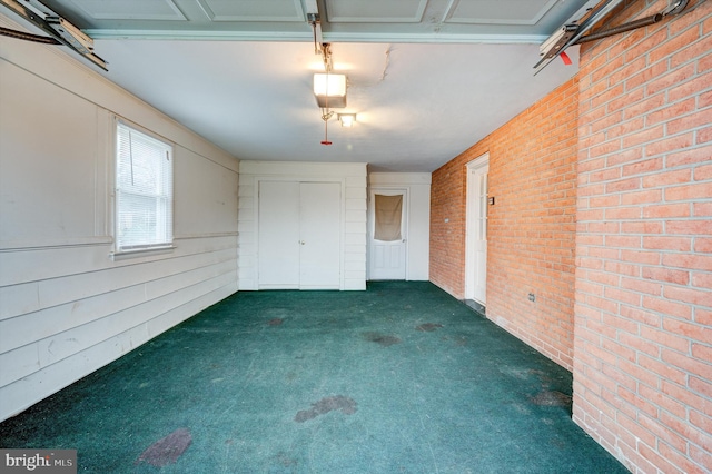 unfurnished bedroom with dark carpet and brick wall