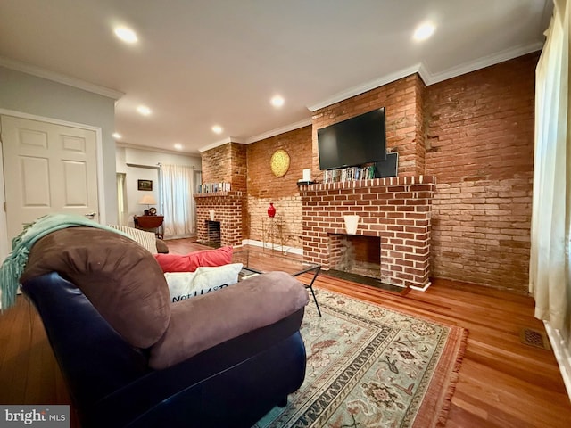 living room with light hardwood / wood-style floors, ornamental molding, brick wall, and a brick fireplace