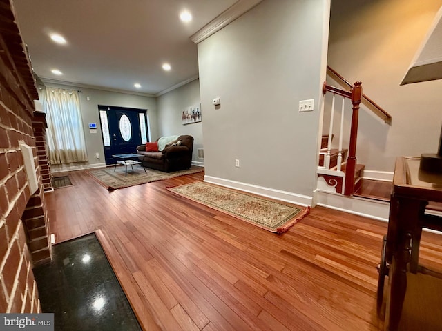 foyer featuring hardwood / wood-style flooring, a fireplace, and crown molding