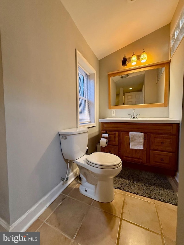 bathroom with tile patterned flooring, vanity, toilet, and lofted ceiling