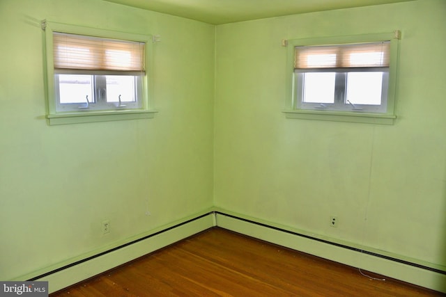 spare room with a baseboard heating unit, dark hardwood / wood-style flooring, and a healthy amount of sunlight