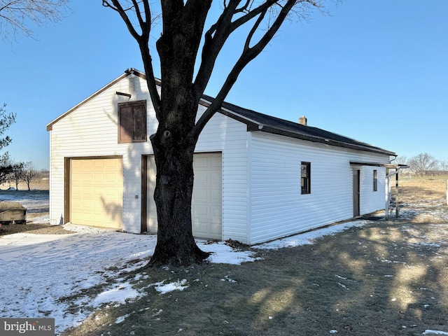 view of snow covered exterior with an outbuilding and a garage