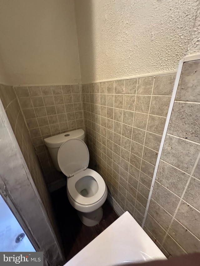 bathroom with toilet and tile walls