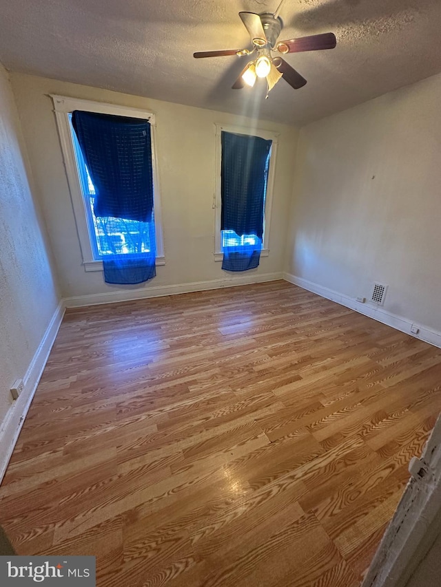 empty room featuring ceiling fan, hardwood / wood-style floors, and a textured ceiling