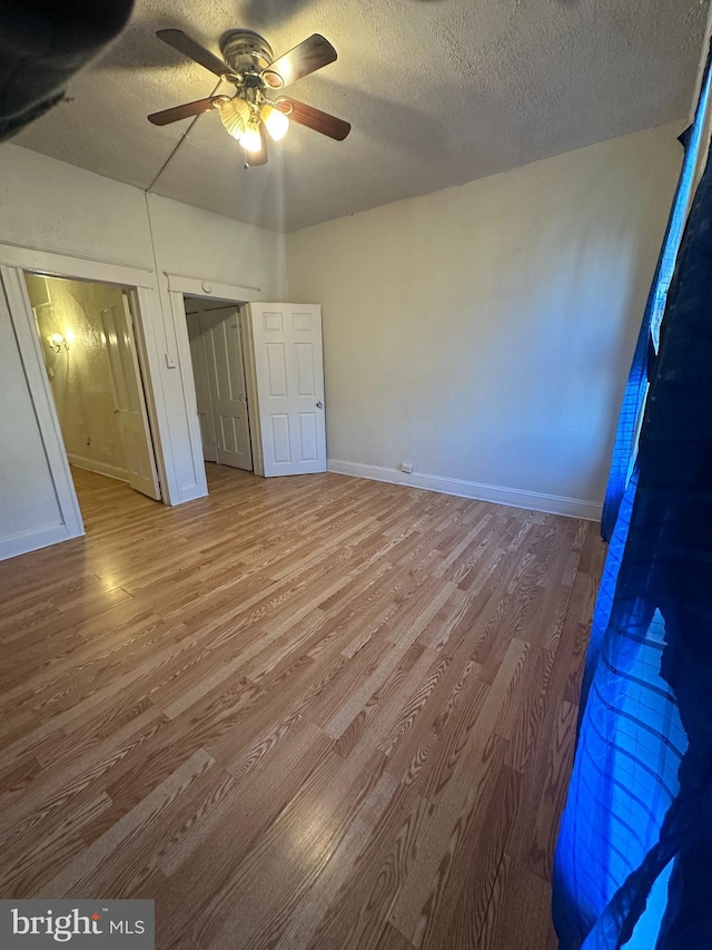 unfurnished bedroom with ceiling fan, light wood-type flooring, and a textured ceiling