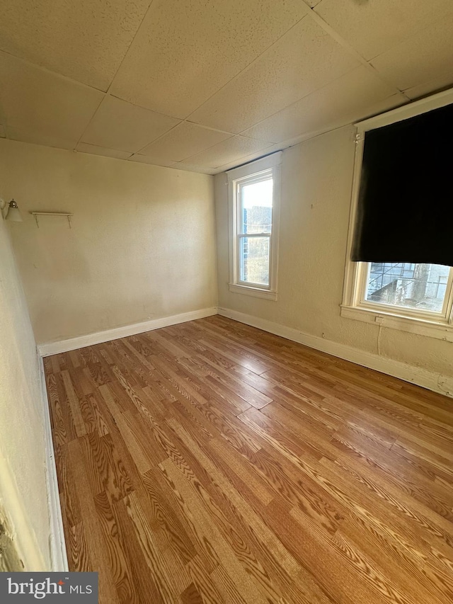 empty room with light wood-type flooring and a drop ceiling