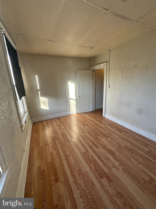 spare room featuring hardwood / wood-style flooring and a drop ceiling