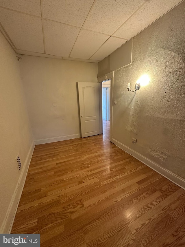 spare room with a paneled ceiling and hardwood / wood-style floors