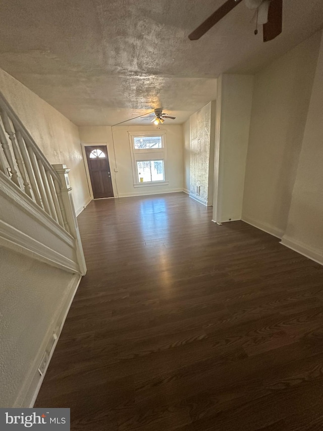 entrance foyer with a textured ceiling, ceiling fan, and dark wood-type flooring