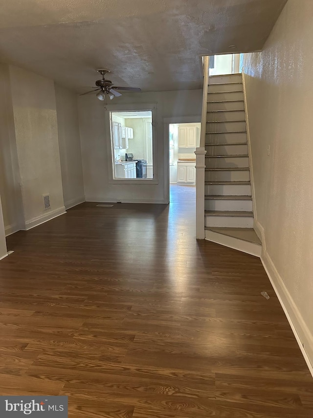 unfurnished living room featuring ceiling fan and dark hardwood / wood-style floors