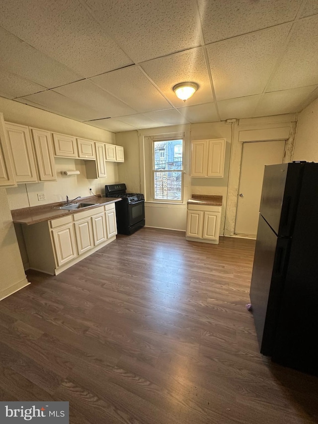 kitchen with black appliances, a paneled ceiling, dark hardwood / wood-style floors, and white cabinets