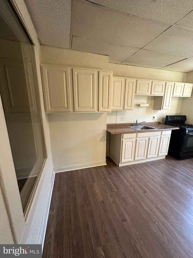 kitchen featuring black gas range, a paneled ceiling, sink, and dark wood-type flooring