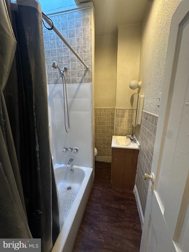 full bathroom featuring vanity, hardwood / wood-style floors, toilet, shower / bathing tub combination, and tile walls