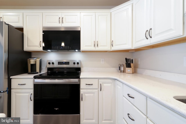 kitchen with light stone counters, white cabinets, and appliances with stainless steel finishes