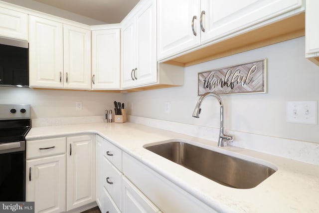 kitchen featuring white cabinetry, sink, light stone countertops, and appliances with stainless steel finishes