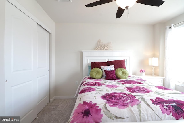 carpeted bedroom with ceiling fan, multiple windows, and a closet