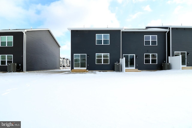 snow covered back of property featuring central AC unit