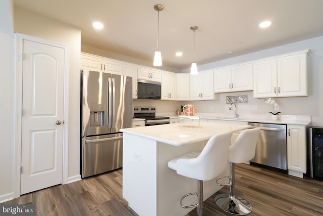 kitchen featuring pendant lighting, a center island, dark wood-type flooring, white cabinetry, and stainless steel appliances