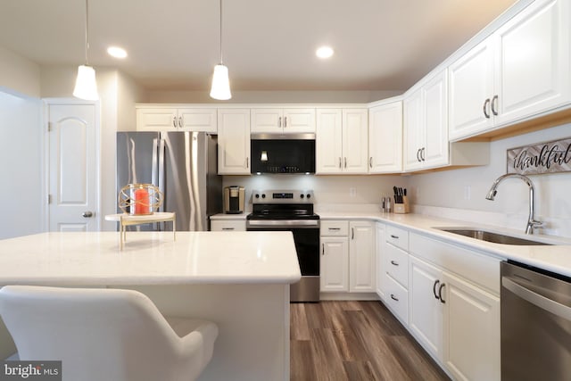 kitchen featuring hanging light fixtures, white cabinetry, sink, and stainless steel appliances