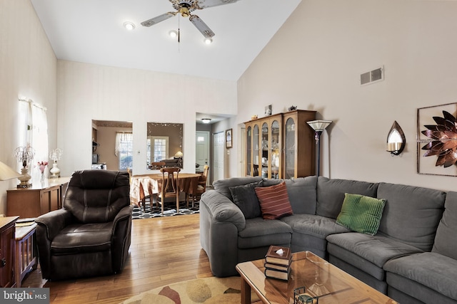 living room featuring light hardwood / wood-style flooring, high vaulted ceiling, and ceiling fan