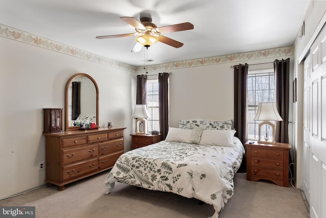 bedroom featuring multiple windows, ceiling fan, and light carpet