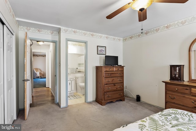 bedroom featuring ensuite bathroom, light colored carpet, ceiling fan, and a closet