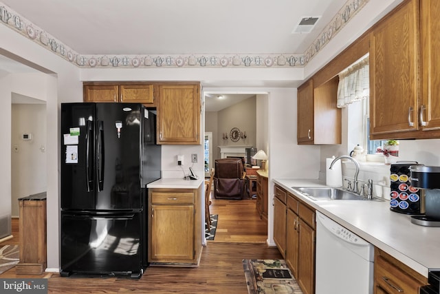 kitchen featuring white dishwasher, sink, dark hardwood / wood-style flooring, and black fridge