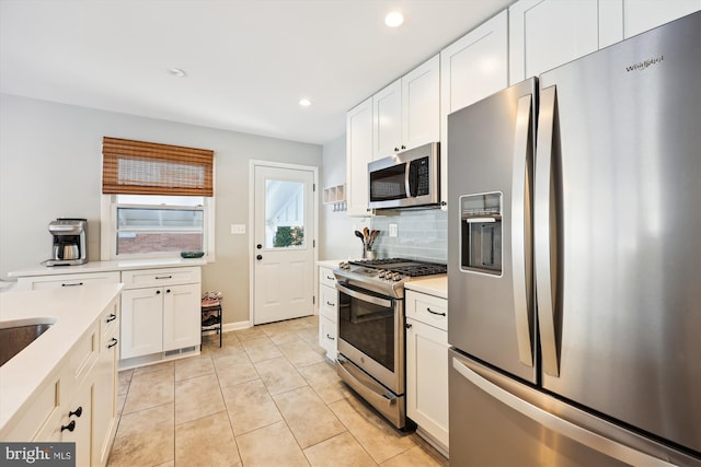 kitchen with backsplash, white cabinetry, light tile patterned floors, and appliances with stainless steel finishes