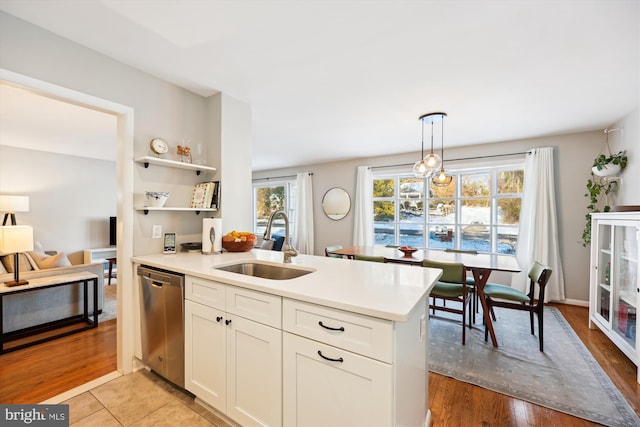 kitchen with kitchen peninsula, sink, pendant lighting, dishwasher, and white cabinetry