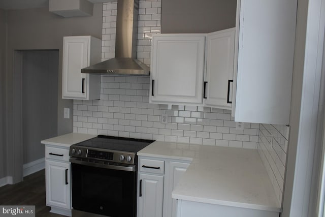 kitchen with decorative backsplash, white cabinetry, wall chimney exhaust hood, and stainless steel electric range