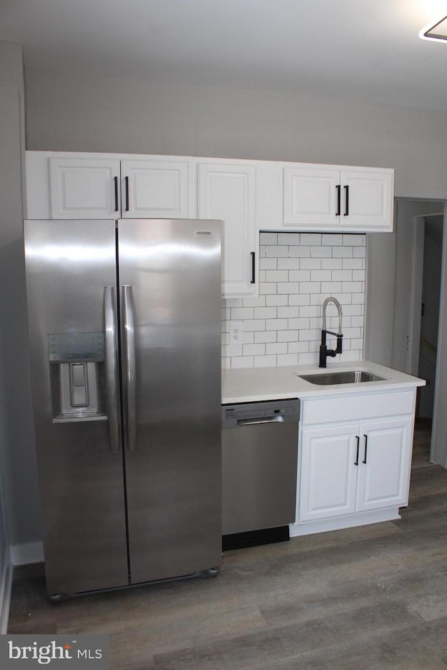 kitchen featuring decorative backsplash, appliances with stainless steel finishes, dark wood-type flooring, sink, and white cabinetry