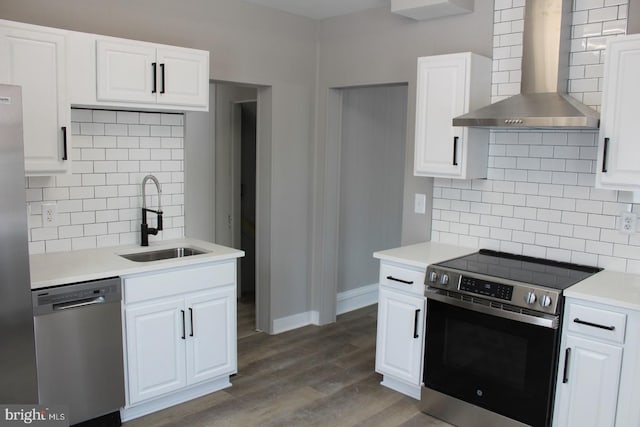 kitchen with white cabinets, sink, stainless steel appliances, and wall chimney range hood