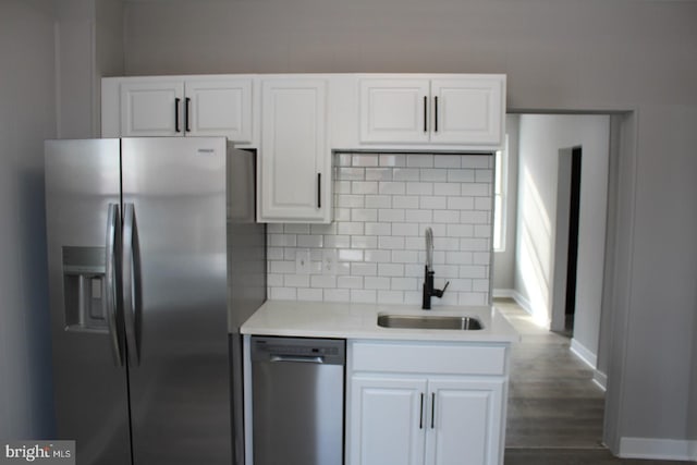 kitchen with sink, dark hardwood / wood-style flooring, decorative backsplash, white cabinets, and appliances with stainless steel finishes