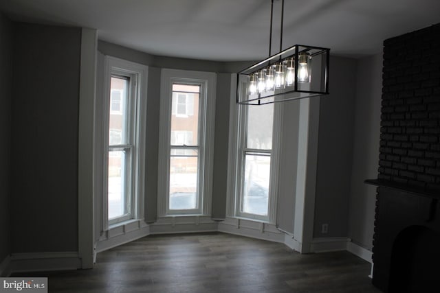 unfurnished dining area with a wealth of natural light, dark hardwood / wood-style floors, and a brick fireplace